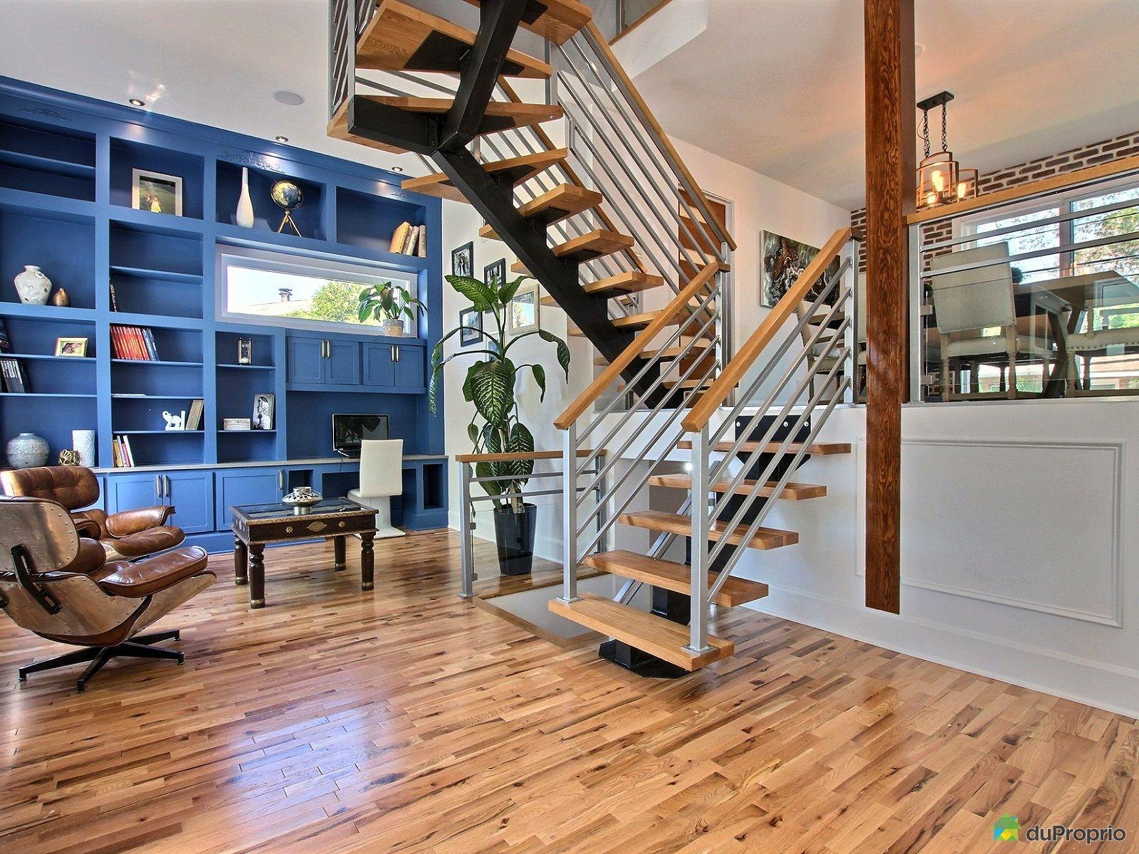 Salon avec escalier ouvert en bois et bibliothèque bleue intégrée
