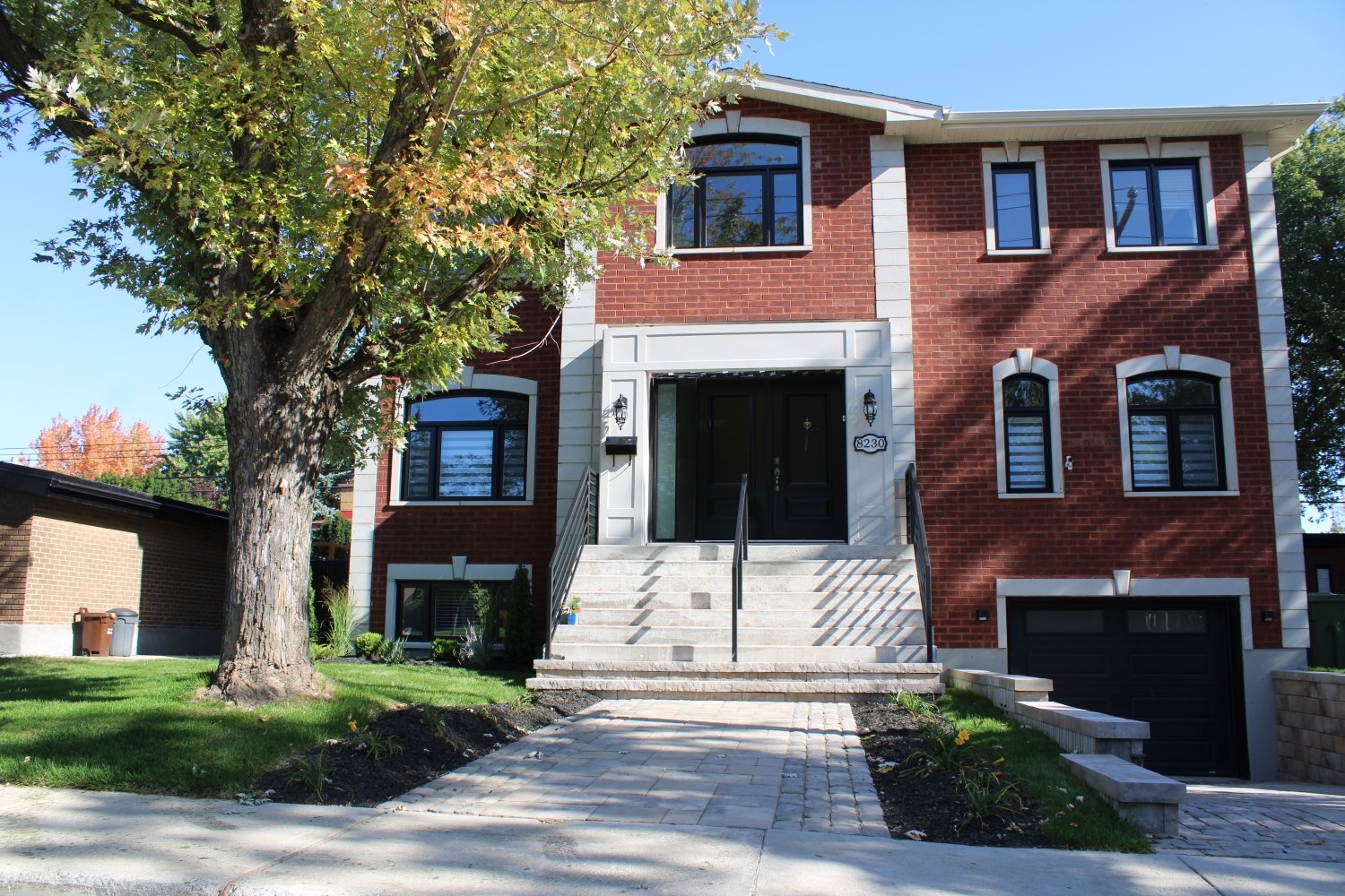 Résidence neuve en brique rouge avec escalier d’entrée et garage
